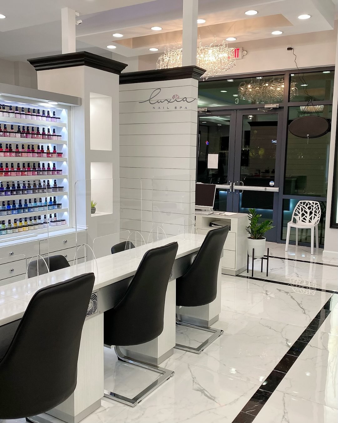 Manicure stations with marble counters and elegant black chairs